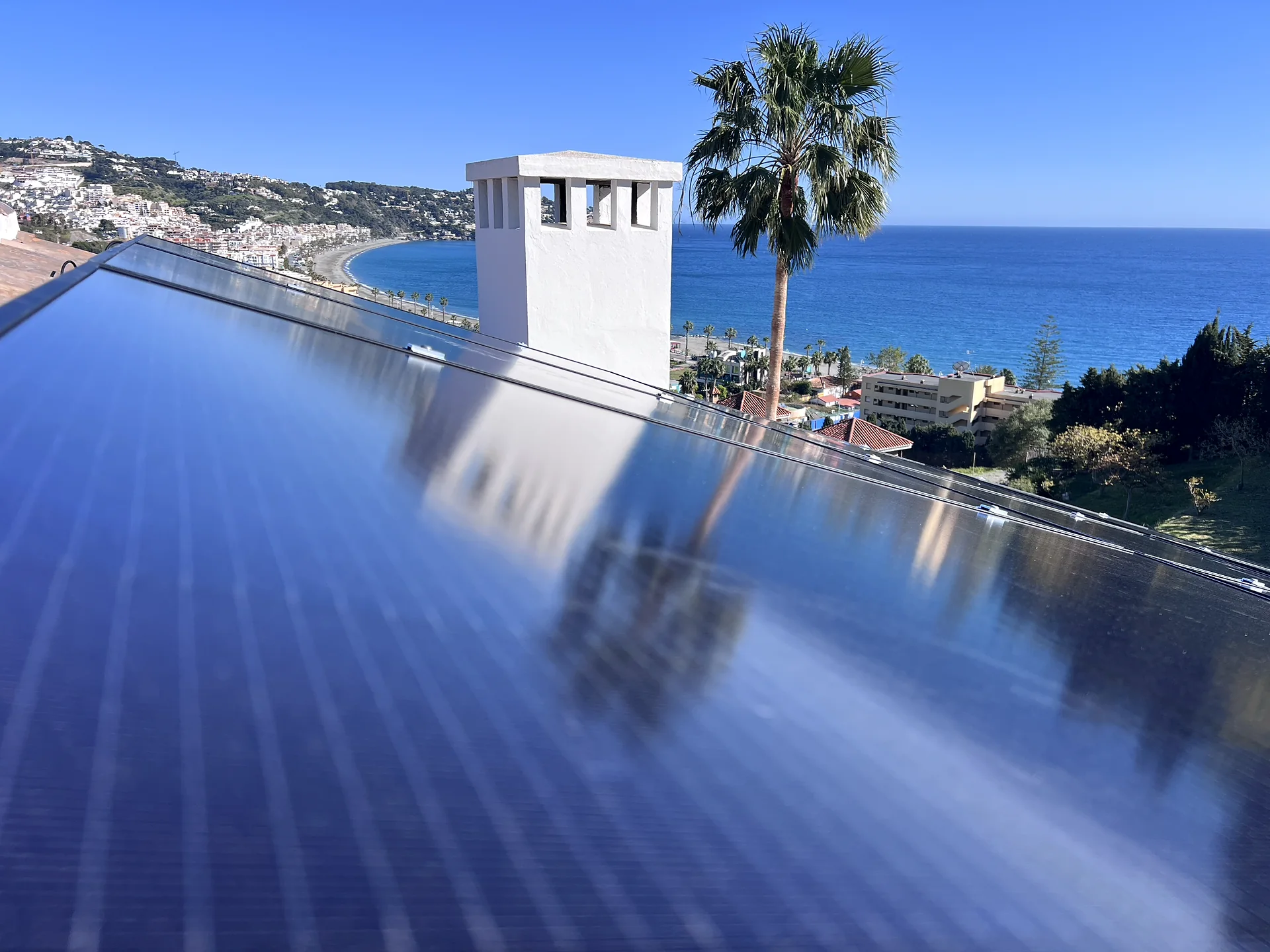 Primer plano de los paneles solares integrados en cubierta con el Mediterráneo al fondo
